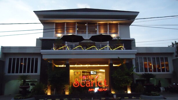 A hotel with a prominent neon sign, a two-story structure, and a balcony with plants. - Hotel Scarlet Makassar (Makassar)