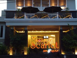 The exterior of the Scarlet Hotel with a prominent illuminated sign, a balcony with umbrellas, and decorative string lights. - Hotel Scarlet Makassar (Makassar)