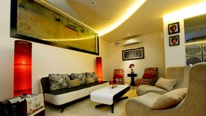 A modern living room with a sofa, armchair, and coffee table. - Hotel Scarlet Makassar (Makassar)