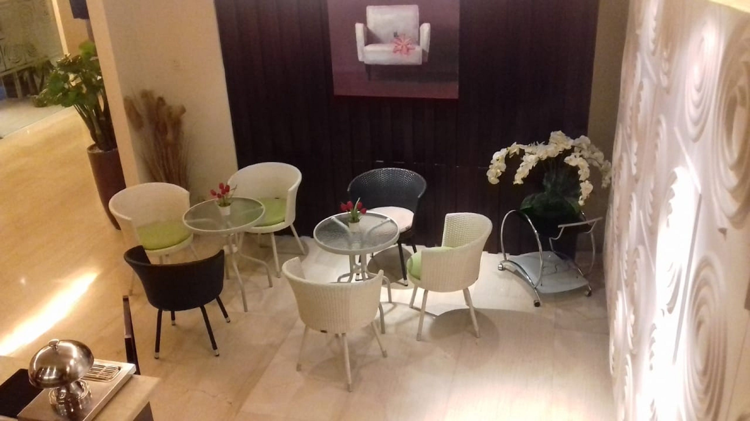 A modern interior with a seating area featuring white and black chairs, a glass table, and a potted plant.