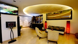 A modern living room with a TV, a bar area, and a sofa. - Hotel Scarlet Makassar (Makassar)