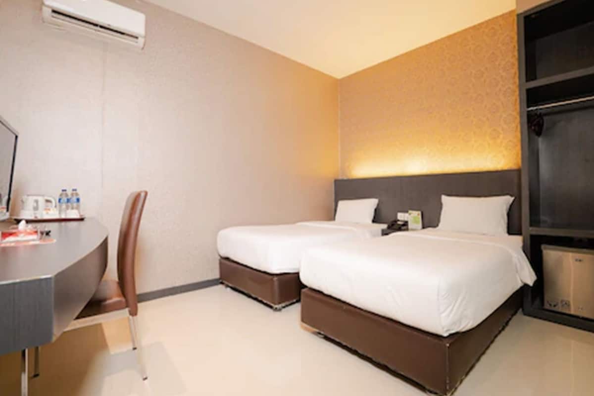 Une chambre d’hôtel avec deux lits, un bureau avec une chaise et une armoire.