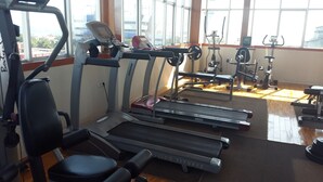 Un gimnasio con cintas de correr, máquinas de pesas y una banca.