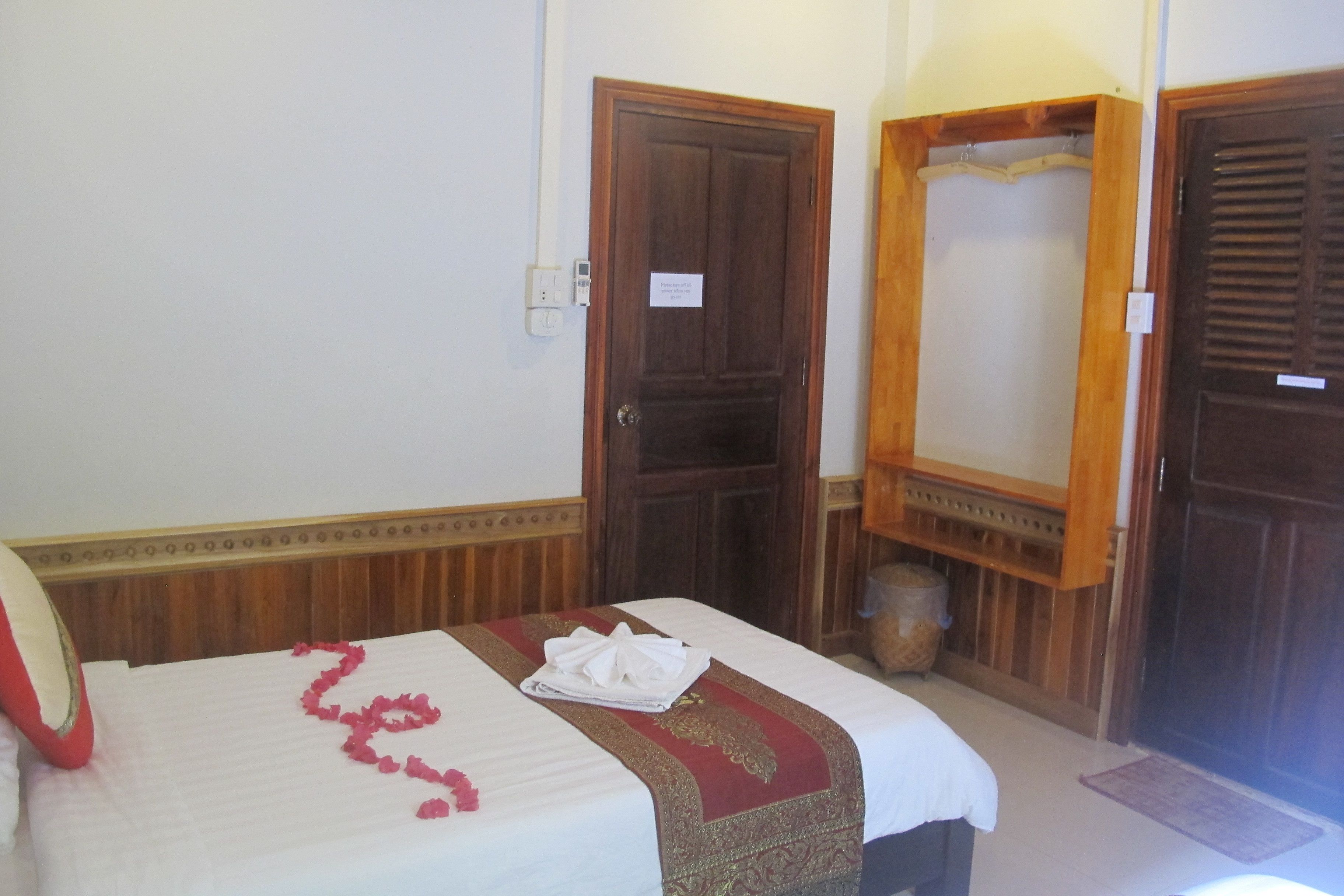 A hotel room with a neatly made bed, wooden doors, and a small basket on the floor.