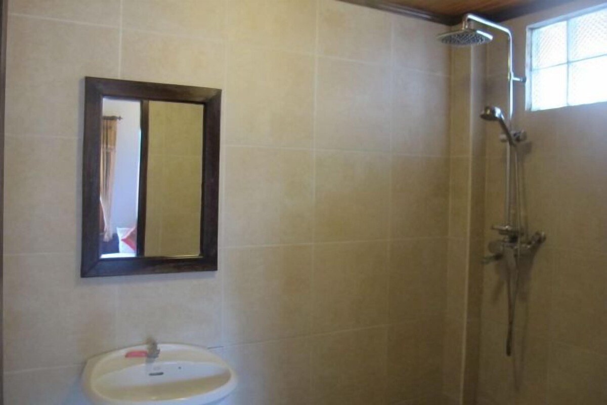 A bathroom with a sink, mirror, and shower.