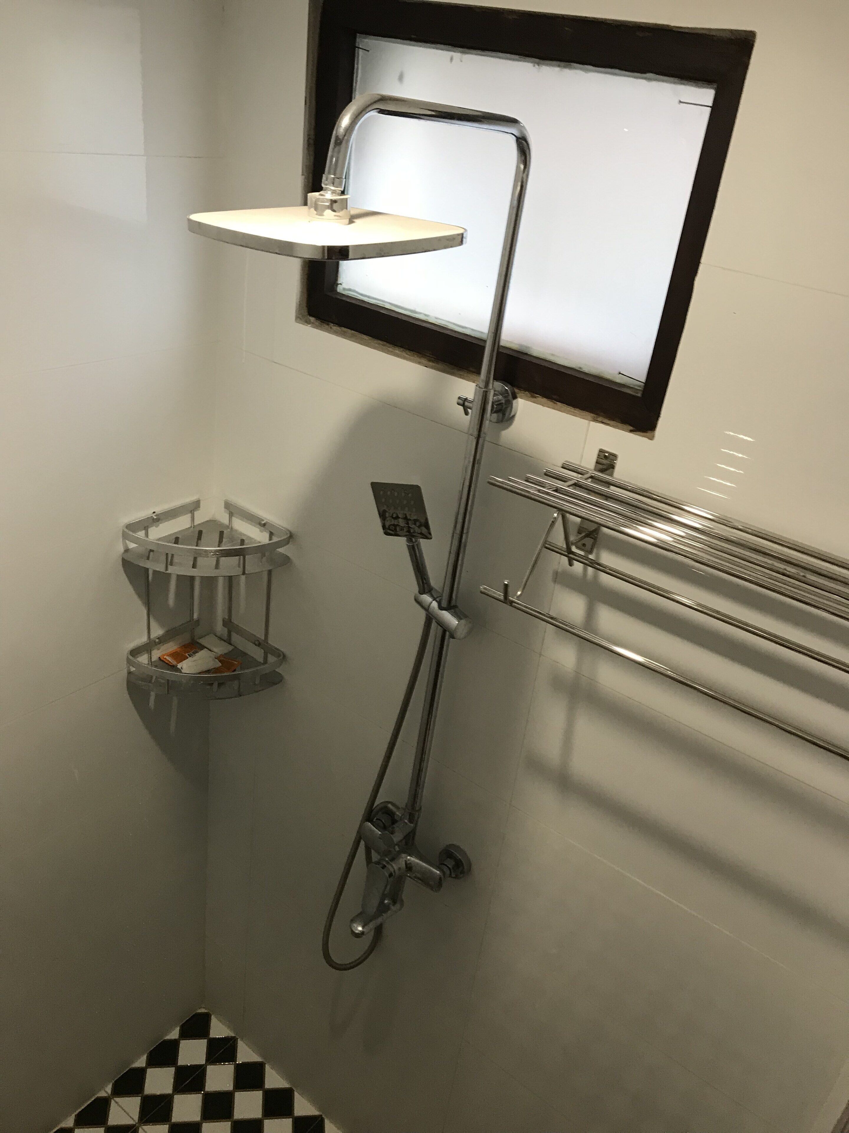 Ein kleines Badezimmer mit Fliesen, einer Dusche, einem Handtuchhalter und einer Seifenschale.