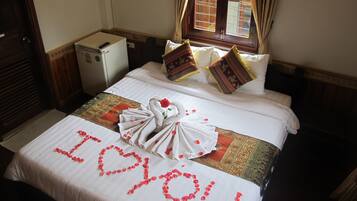 Romantic touches abound in this cozy retreat, featuring a heart-shaped rose petal arrangement and plush bedding.