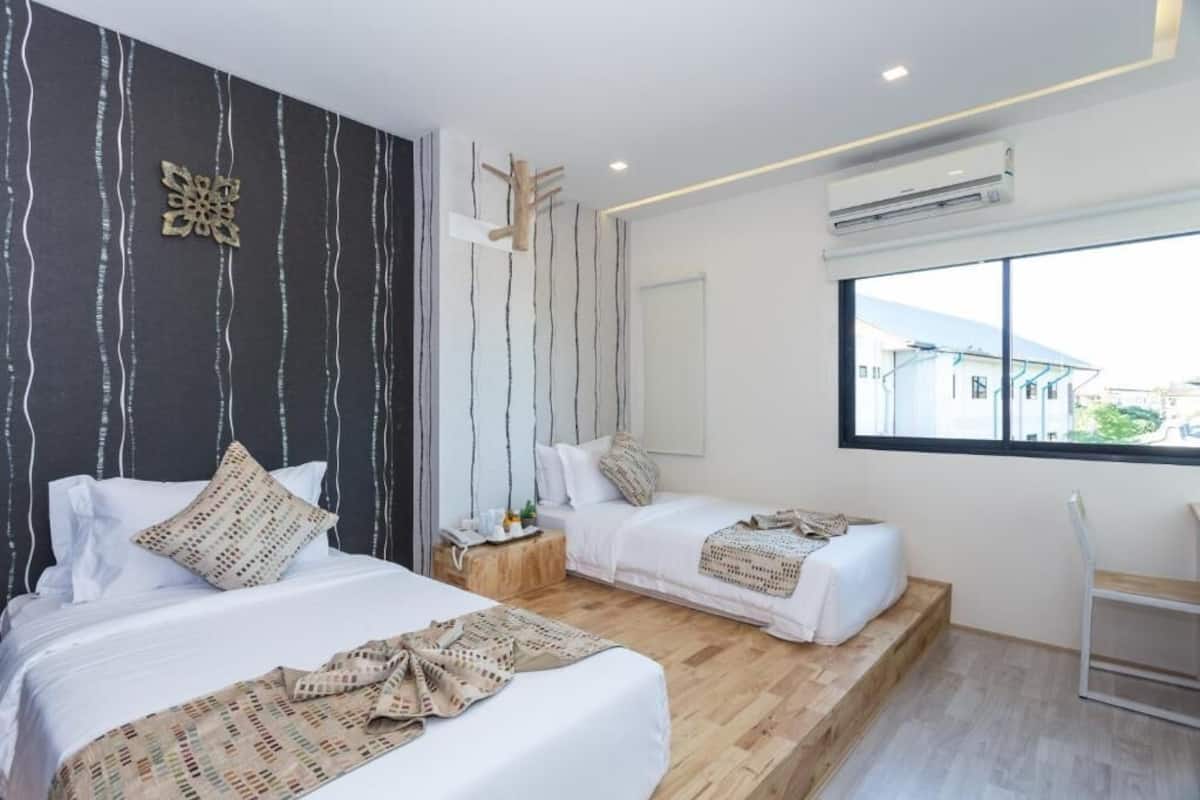 A modern hotel room with two beds, a wooden floor, a large window, and an air conditioning unit.