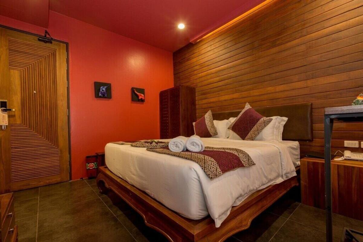 A hotel room with a wooden bed, a red wall, and a wooden ceiling.