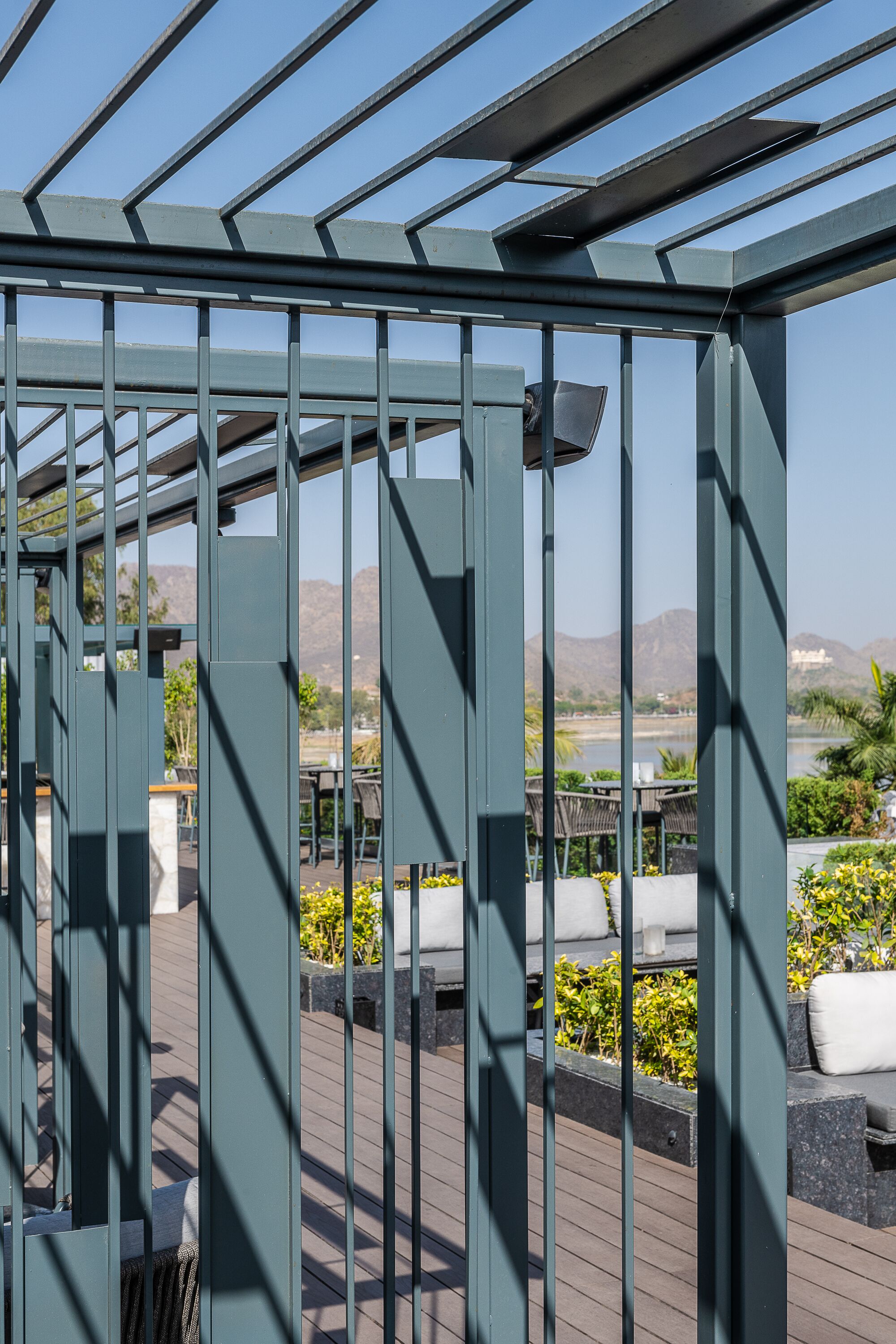 A pergola structure with a view of a landscaped area and distant mountains.