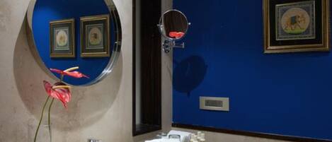 Casa de banho com espelho redondo, lavatório e parede azul decorativa.