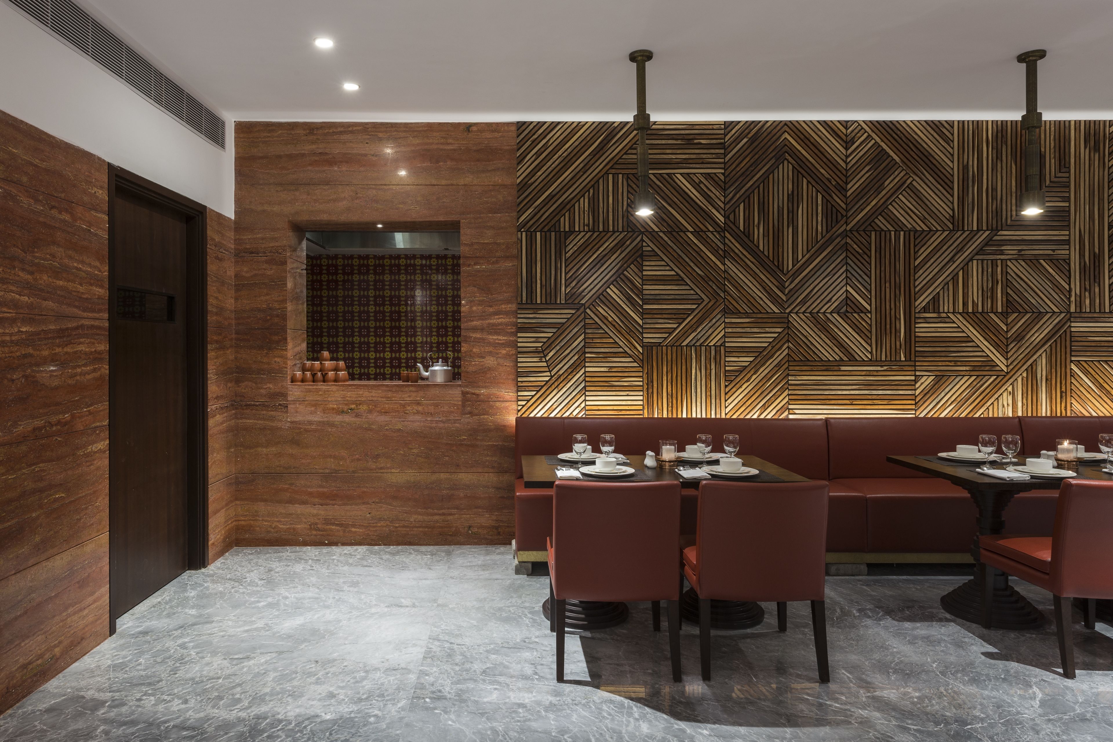 A modern dining area with a geometric patterned wall, a wooden accent wall, and a marble floor.