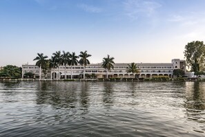 A large, multi-story building with a symmetrical facade, arched windows, and a central entrance. - Hotel Lakend (Udaipur)