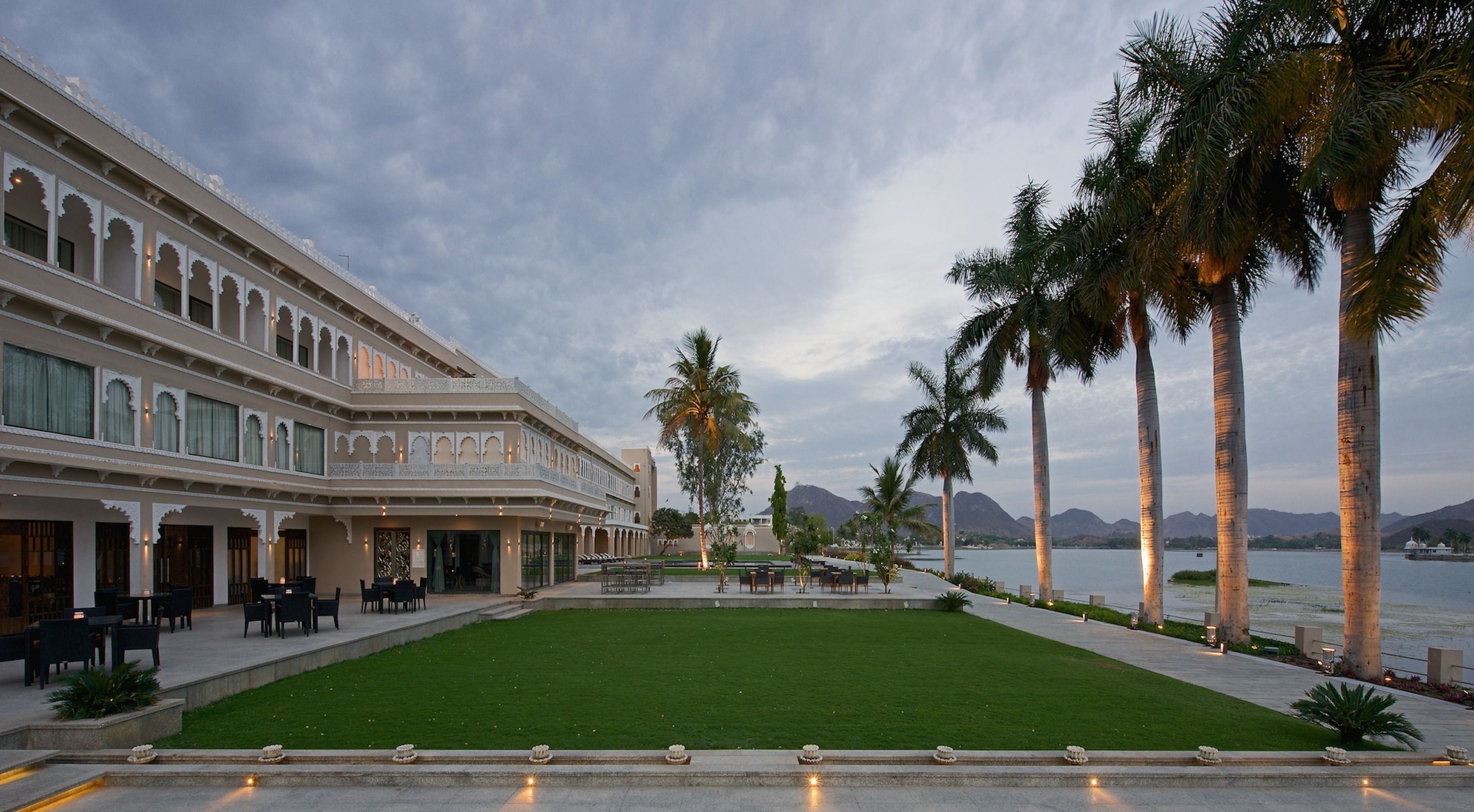 A hotel with a courtyard, palm trees, and a view of mountains.