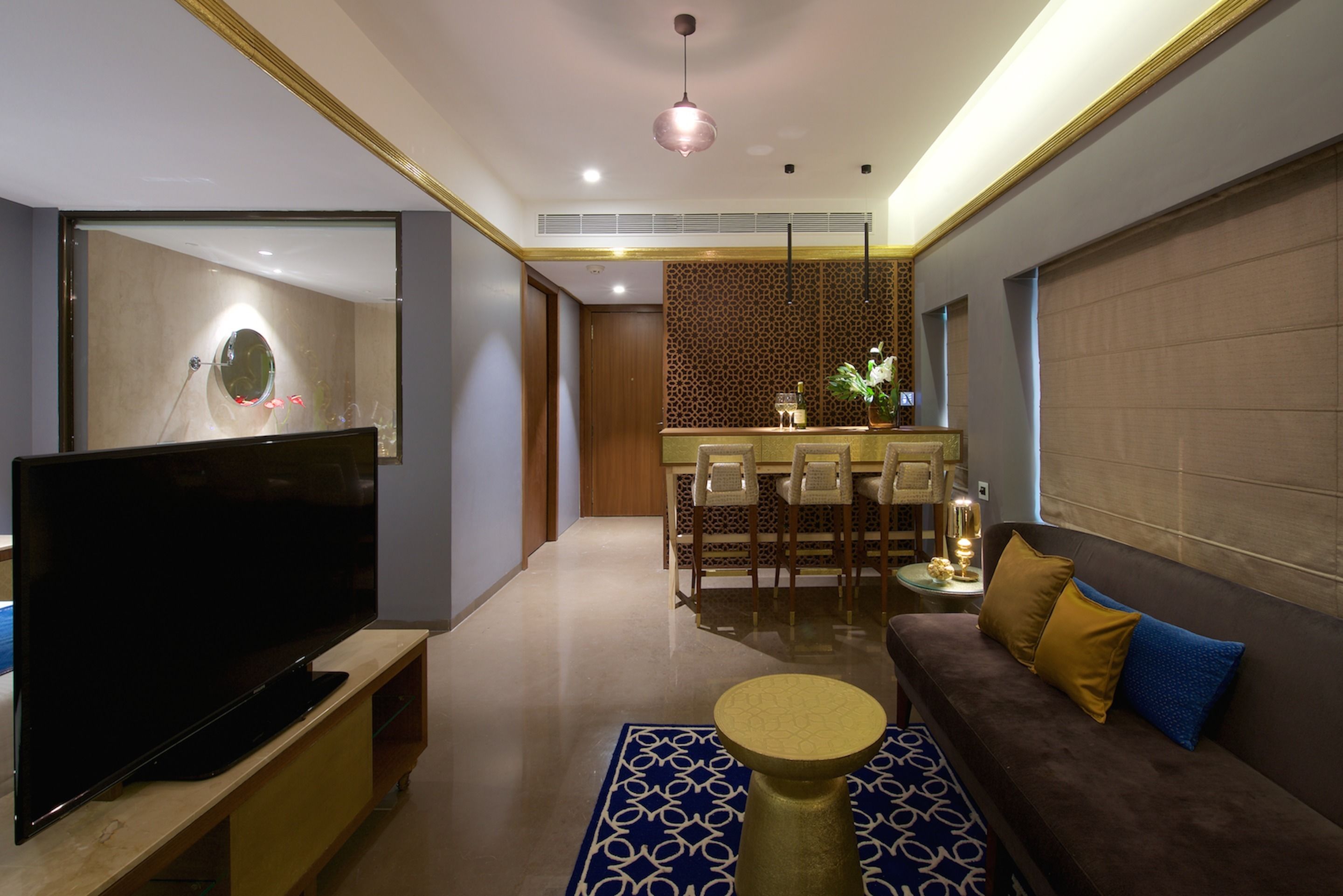 A modern living room with a flat-screen TV, a sofa, a coffee table, and a dining area with a kitchen in the background.