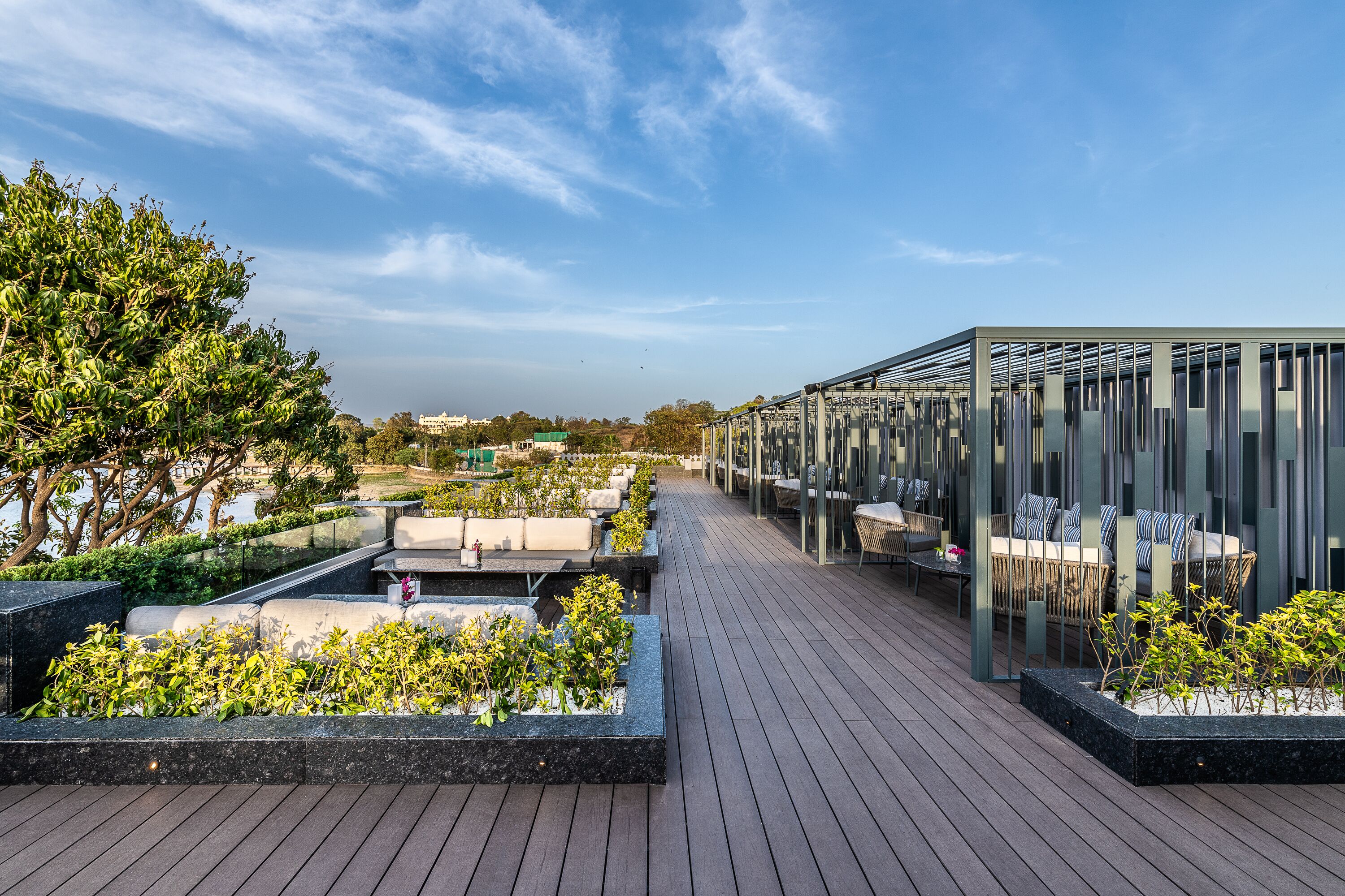 Una terrazza sul tetto con zone salotto, fioriere e una struttura in vetro.