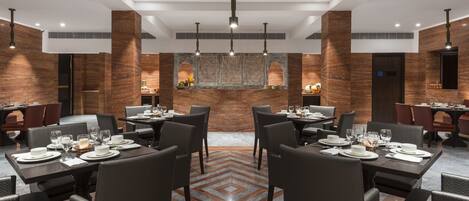 Un restaurant moderne avec des tables et des chaises hautes, un sol à motifs et des murs en bois qui servent d’éléments décoratifs.