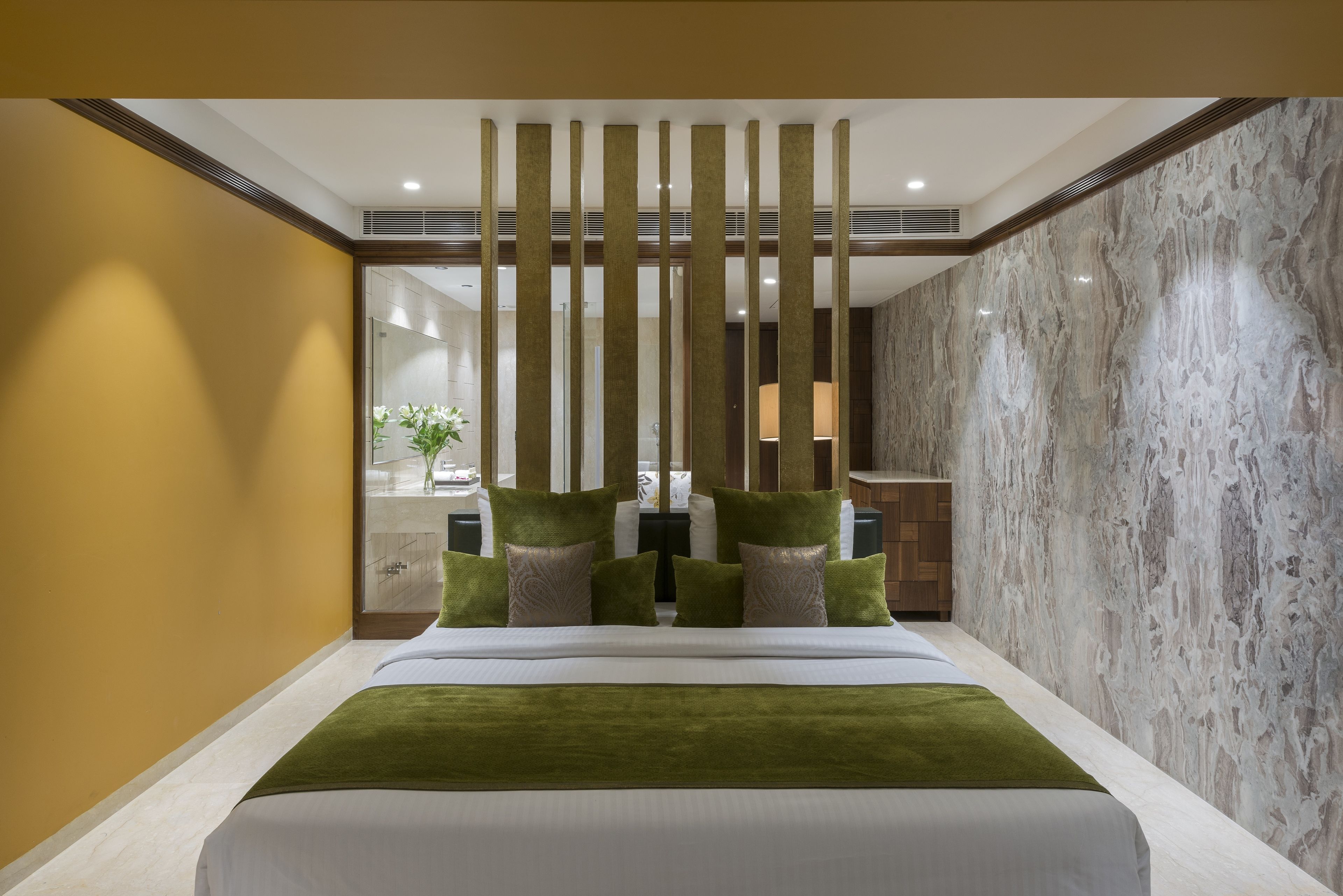 Habitación de hotel moderna con una cama grande, una pared de mármol y vistas al baño.