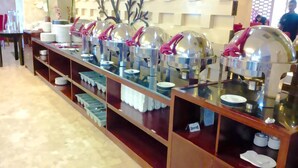 A buffet setup with multiple food stations, each with a dome cover and pink handles. - Travellers Hotel Phinisi (Makassar)