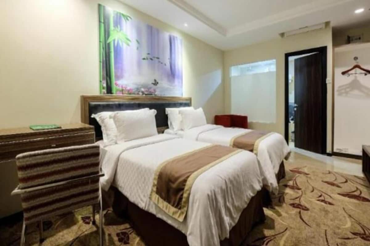 Habitació d'hotel amb un llit gran, una petarrera, un quadre a la paret i una porta amb penjador.