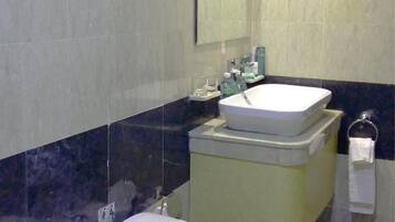 Een badkamer met toilet, wastafel en spiegel.