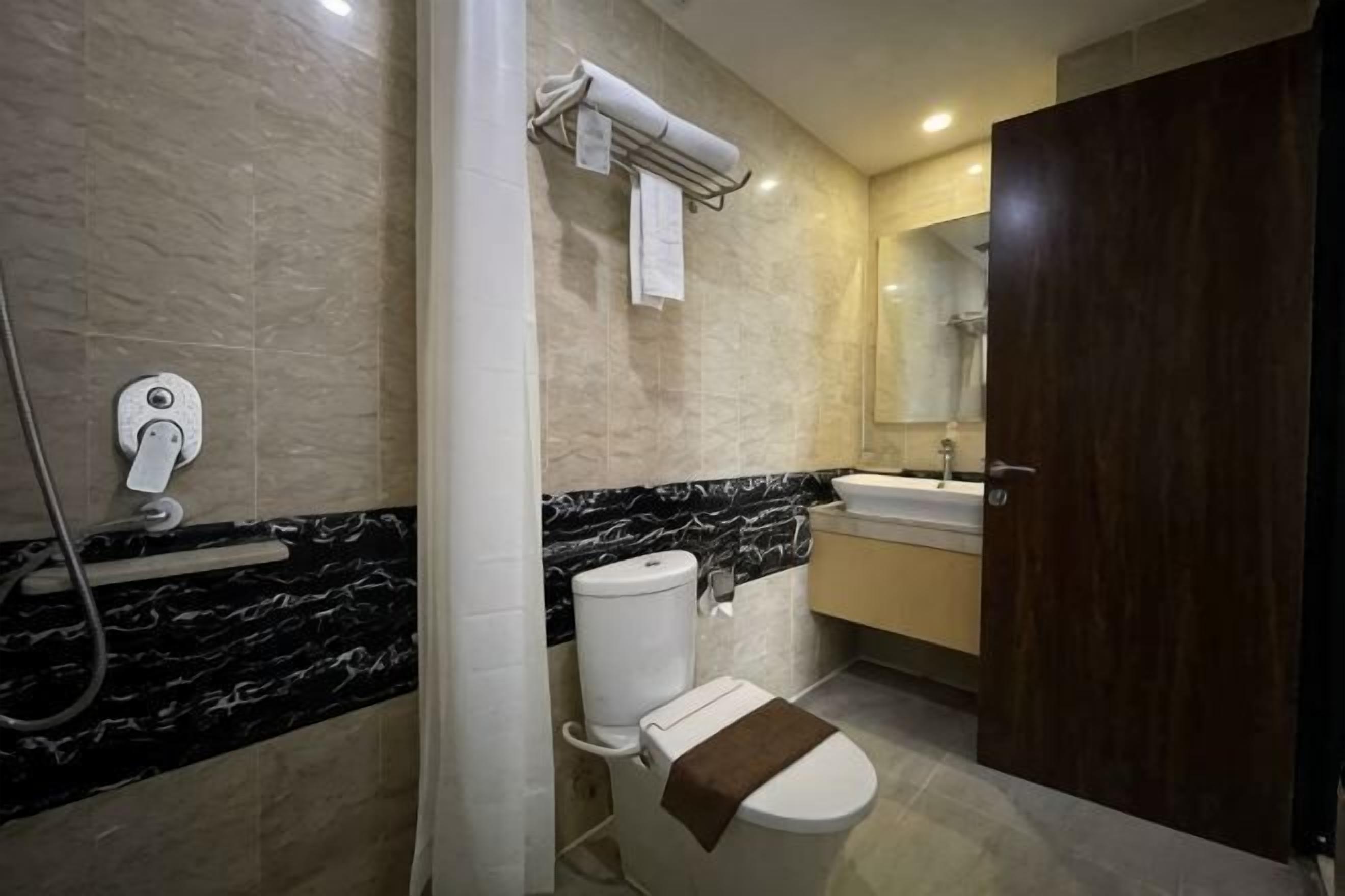 A bathroom with a toilet, a shower, a sink, and a mirror.