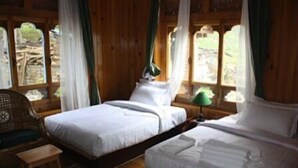 A room with two single beds, a wooden chair, a small table, and a patterned rug. - Taktsang Boutique Resort & Spa (Paro)