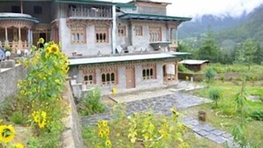 A traditional building with multiple levels and balconies, surrounded by greenery and a mountainous backdrop. - Taktsang Boutique Resort & Spa (Paro)