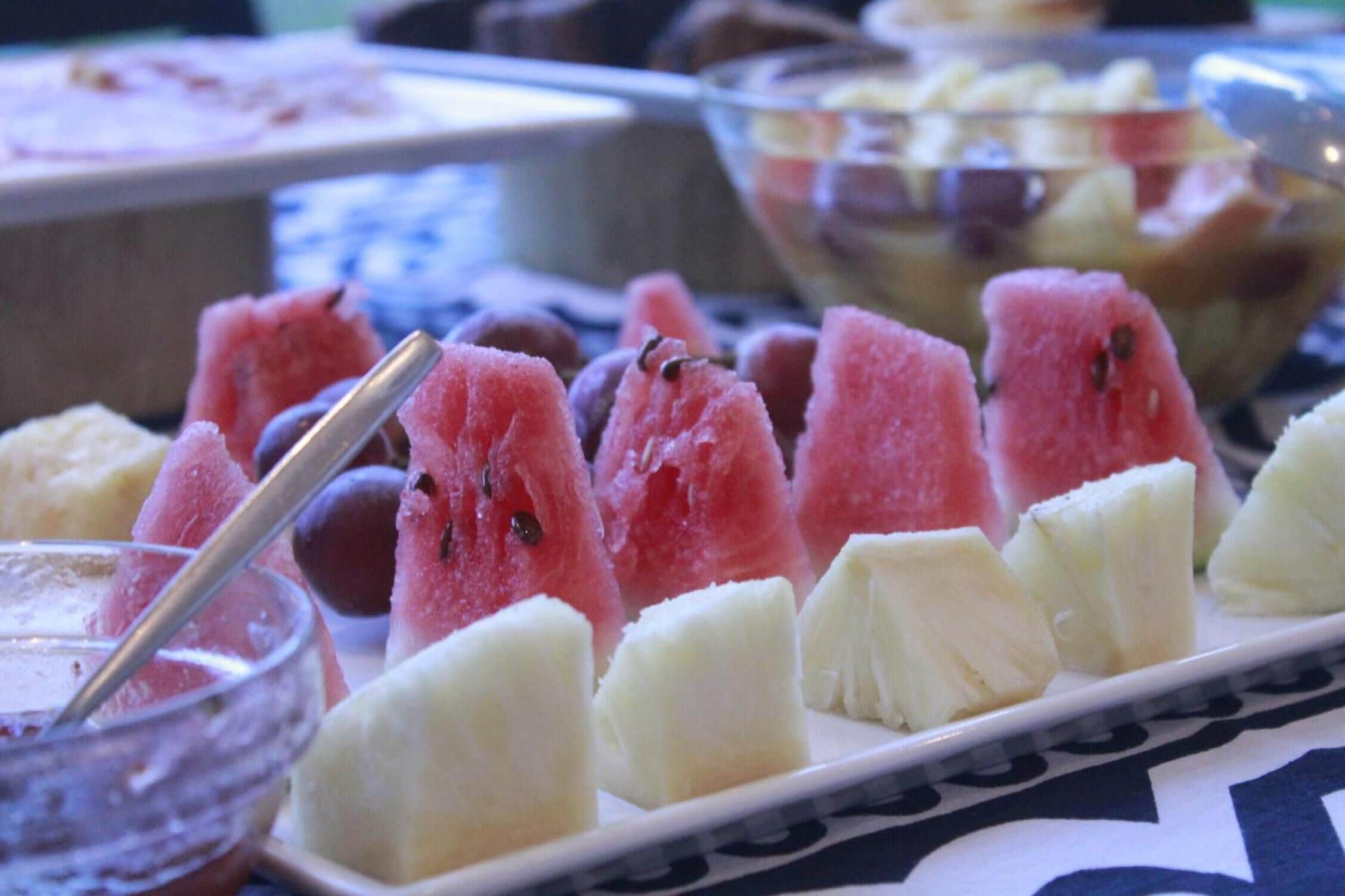 Un bufé con diversas frutas y un tazón de ensalada de frutas.