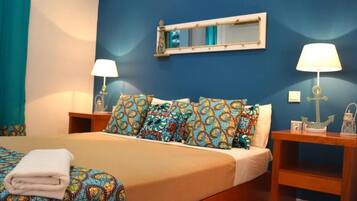 Una habitación de hotel con una cama, dos mesitas de noche con lámparas, un espejo y una pared azul.