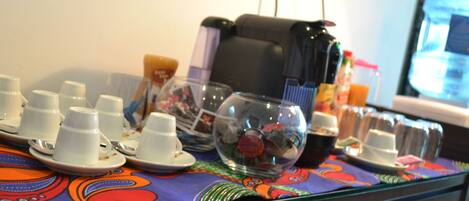 A table with multiple white cups and saucers, a glass bowl, and a black bag.