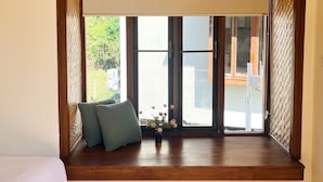 A room with a large window, wooden floor, and a bed with white bedding. - Pai Country Hut (Pai)