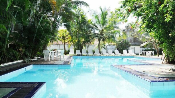 A pool area with multiple swimming pools, surrounded by palm trees and lounge chairs. - The white Haven (Panadura)