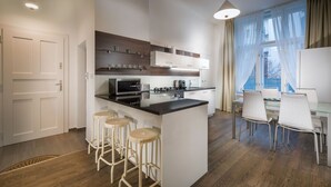 Moderni keittiö, jossa on keskeinen keittiösaareke, baarituolit ja ruokailutila tuoleineen.