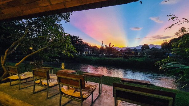 A riverside view with wooden benches and a thatched roof structure. - Canary Guesthouse (Pai)