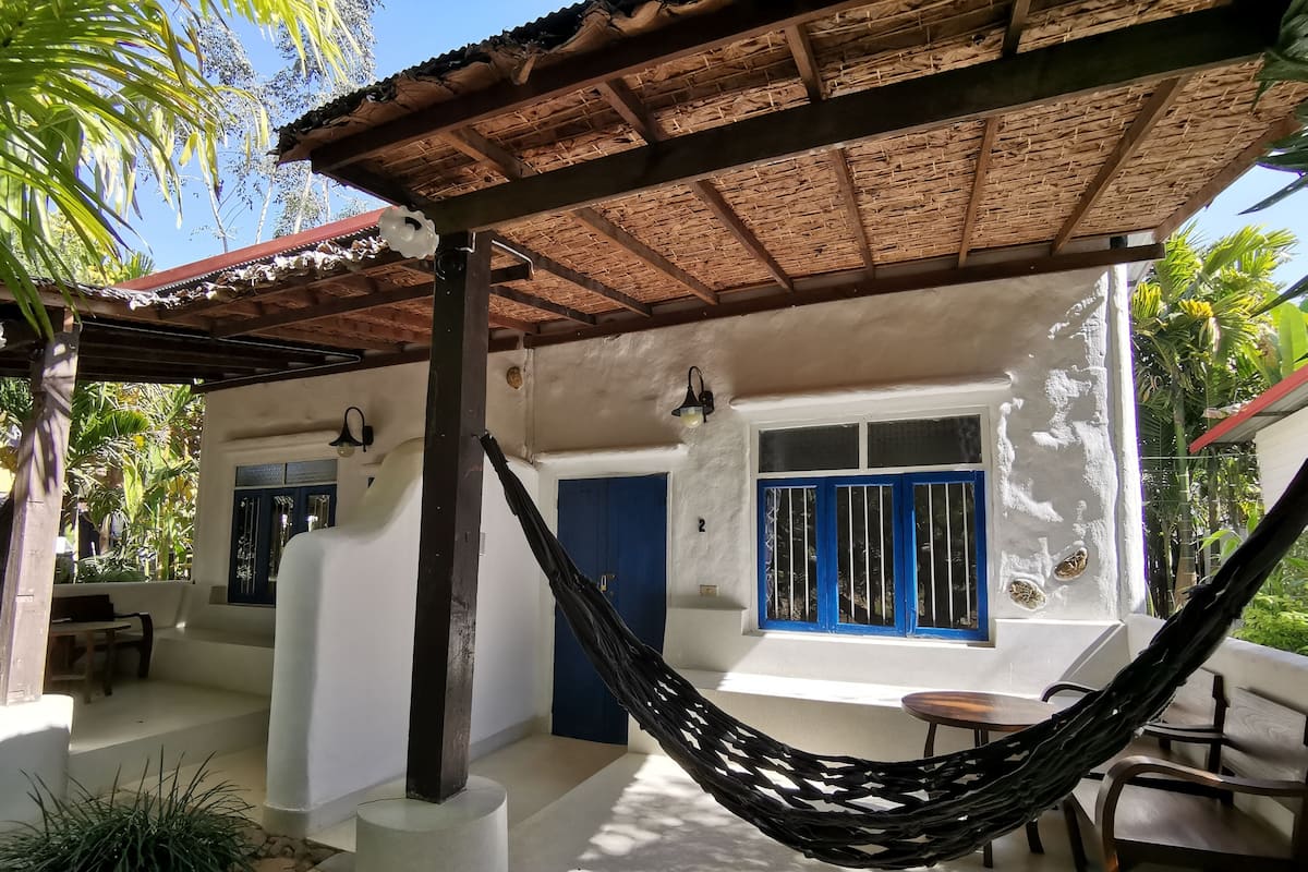 Un espacio al aire libre techado con una hamaca, un banco y una mesa.