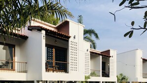 A modern two-story house with a balcony, large windows, and a garden area. - Canary Guesthouse (Pai)