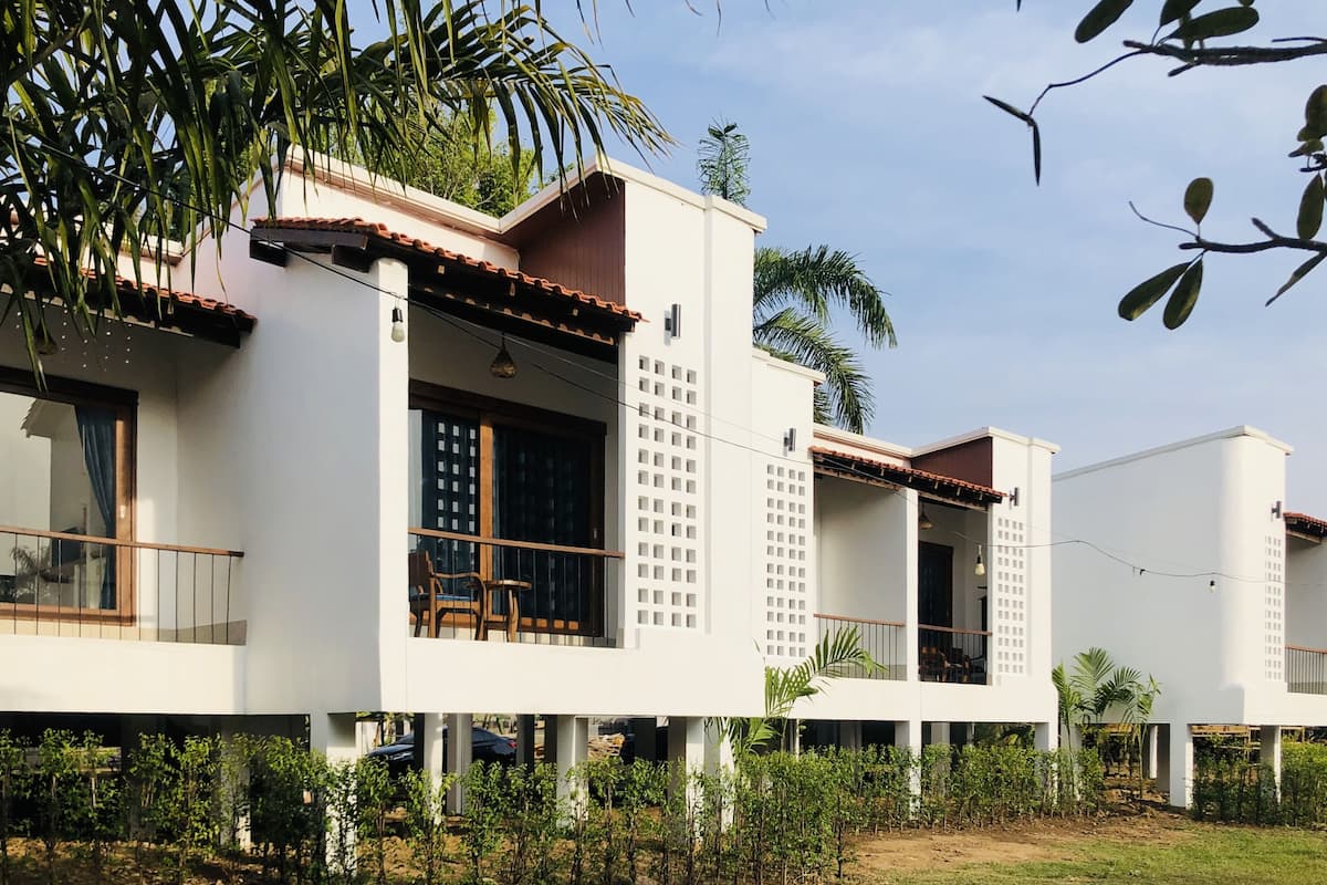 Una casa moderna de dos pisos con balcón, ventanas grandes y un jardín.