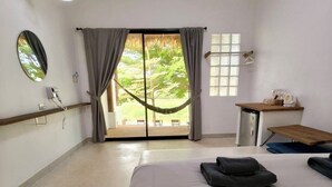 A hotel room with a bed, a desk, a chair, a window with curtains, a hanging chair, and a view of the outdoors. - Canary Guesthouse (Pai)