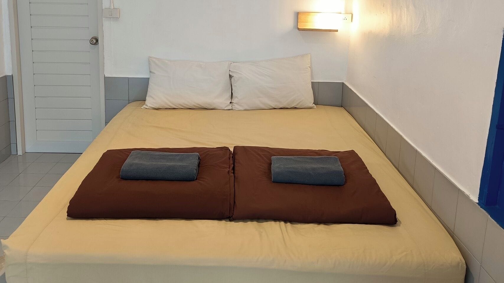 A bed with two pillows, a bedside lamp, and a door.