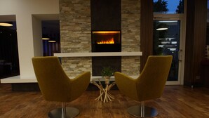 Een moderne woonkamer met een open haard, twee gele fauteuils en een houten vloer.