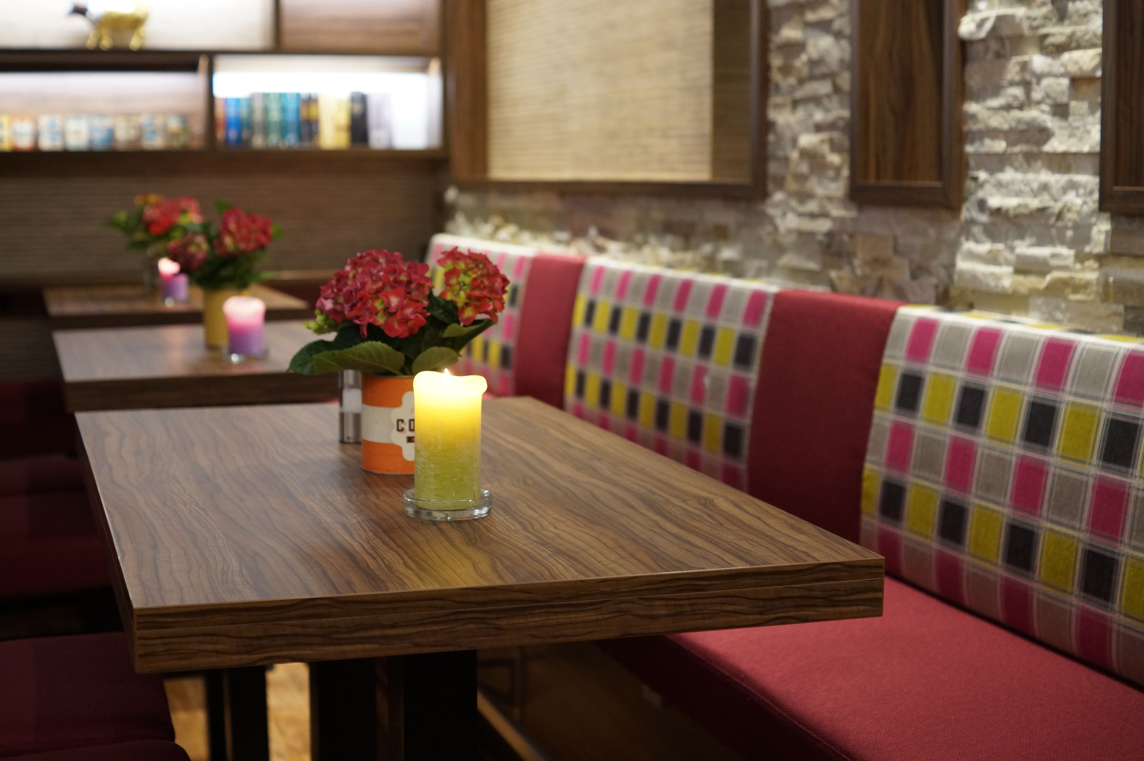 Un interior de restaurante con mesas de madera, cabinas acolchadas y una pared de piedra.