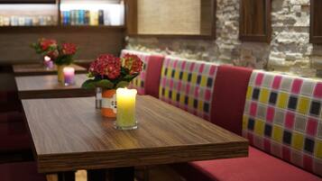 Un interior de restaurante con mesas de madera, cabinas acolchadas y una pared de piedra.