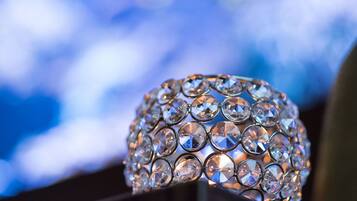A close-up of a crystal-adorned lamp against a blurred blue background.