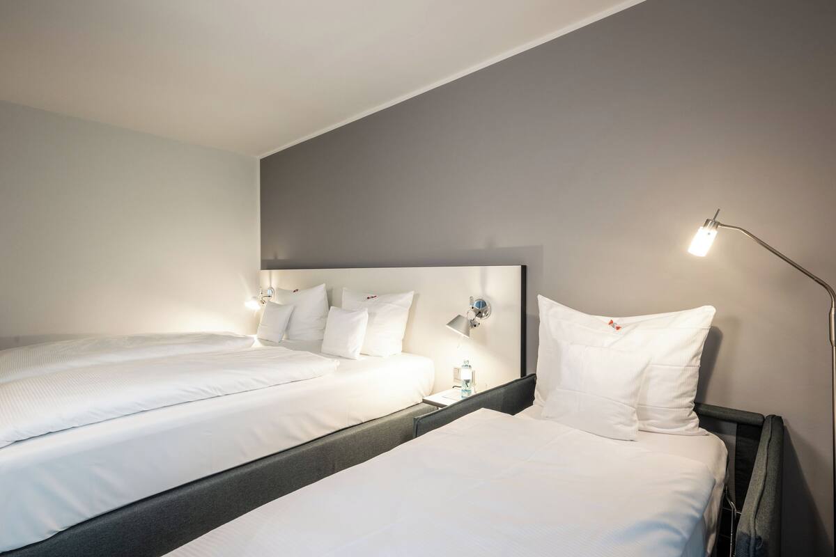Een hotelkamer met twee bedden, een nachtkastje, een lamp en een wandlamp.