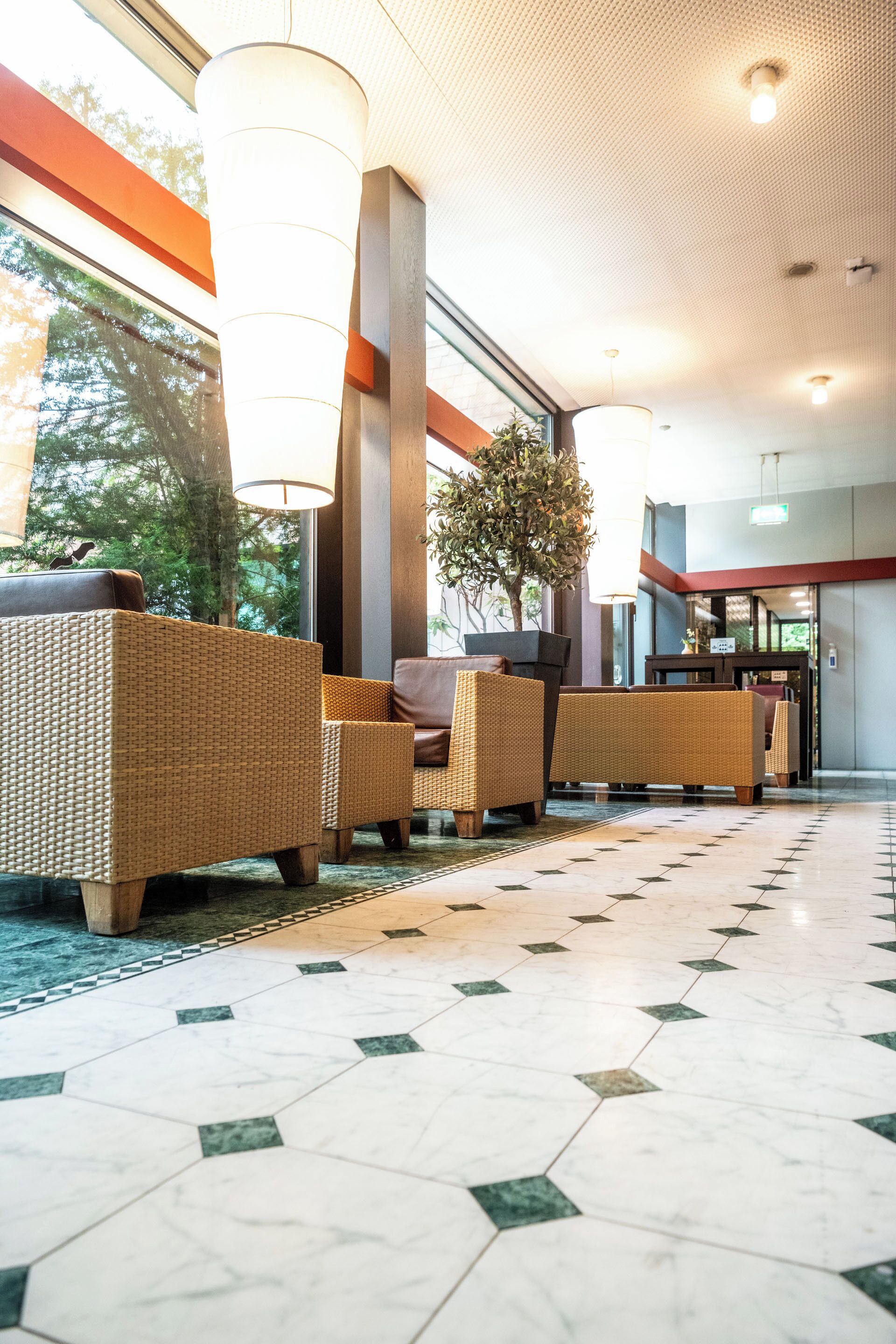 Um hall com móveis de vime, uma planta grande e piso de azulejos.