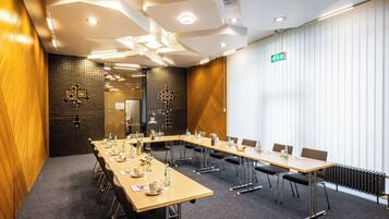 Ein Konferenzraum mit langem Tisch, Stühlen und einer gefliesten Wand.