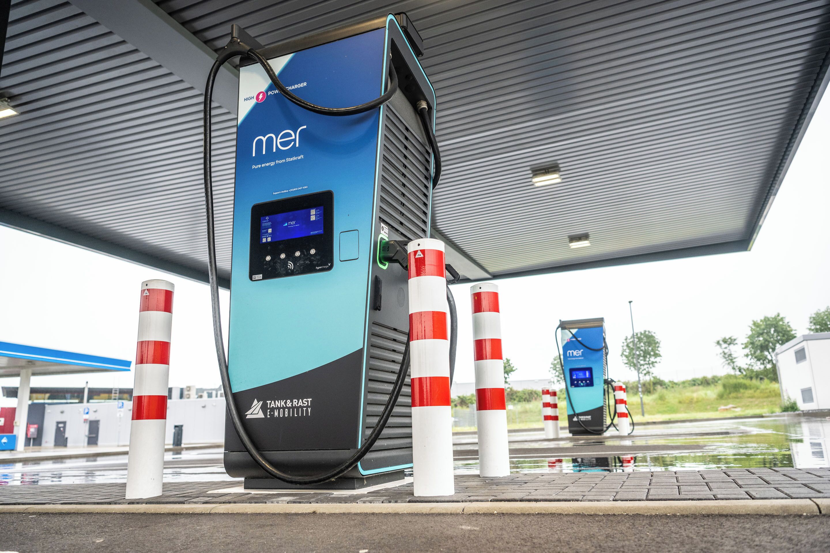 Una estación de carga con pantalla digital, con la marca 'mer' y 'TANK & RAST E-MOBILITY'.