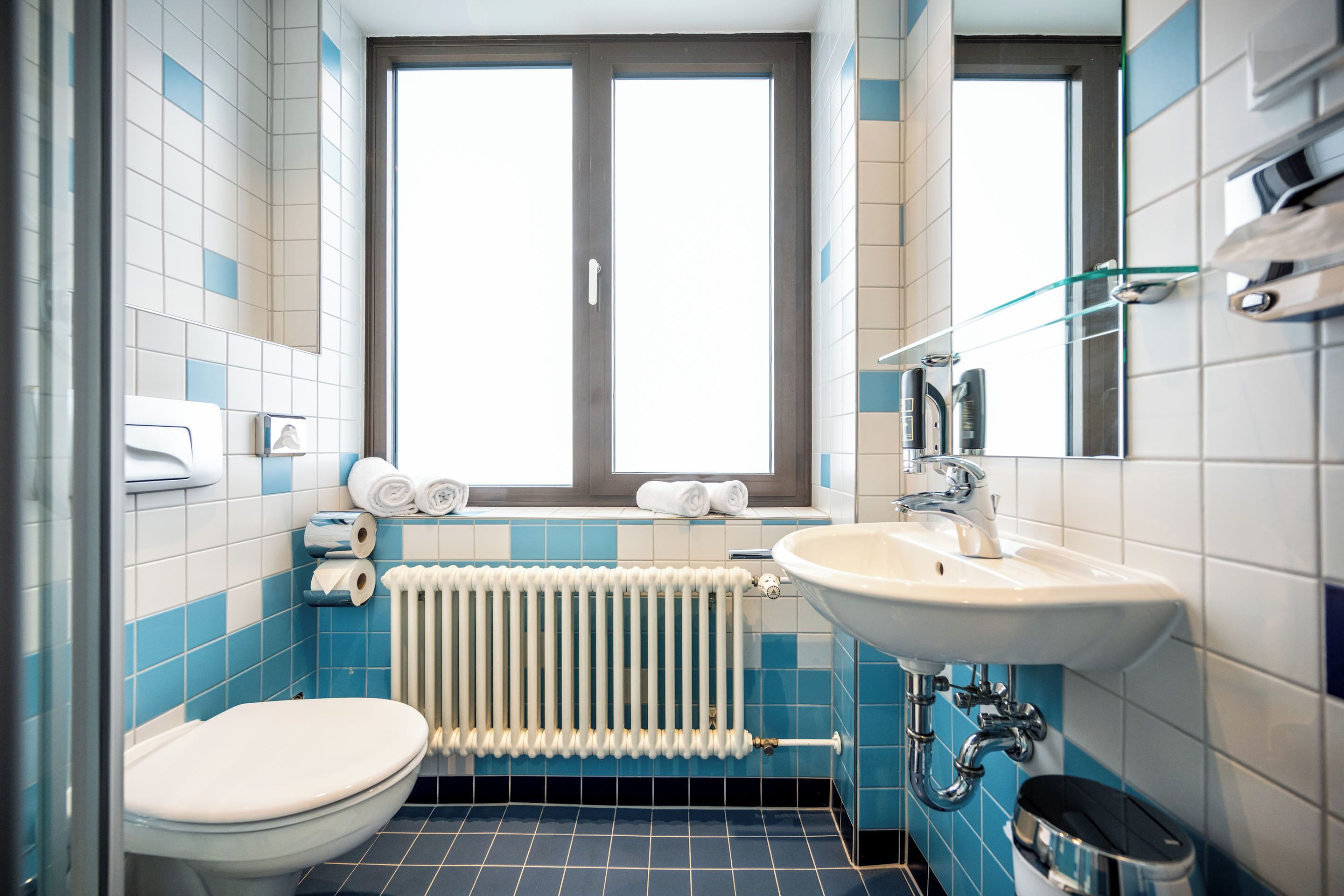 A modern bathroom with a toilet, sink, and window.