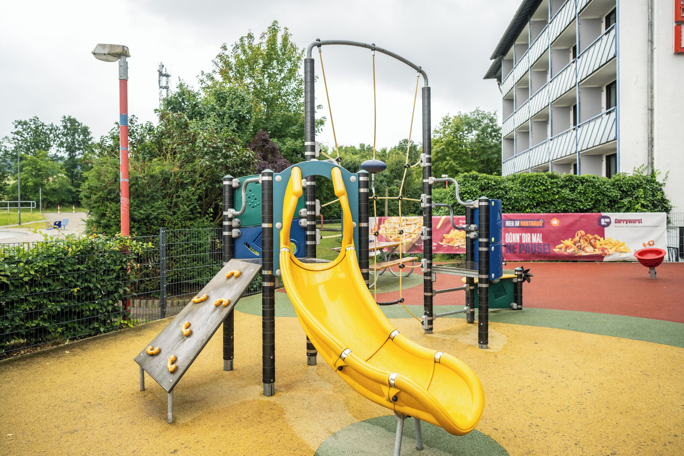 A playground with a yellow slide, climbing structures, and a red and yellow play area.